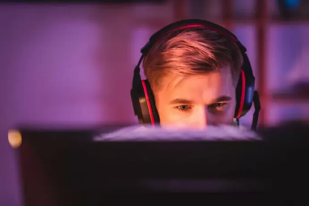 Um rapaz olhando monitor e jogando